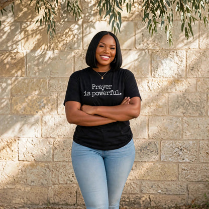 Black woman with sleek black bob wearing black Prayer is powerful Christian t-shirt with exact font Prayer is powerful period, hand on hip, serene smile
